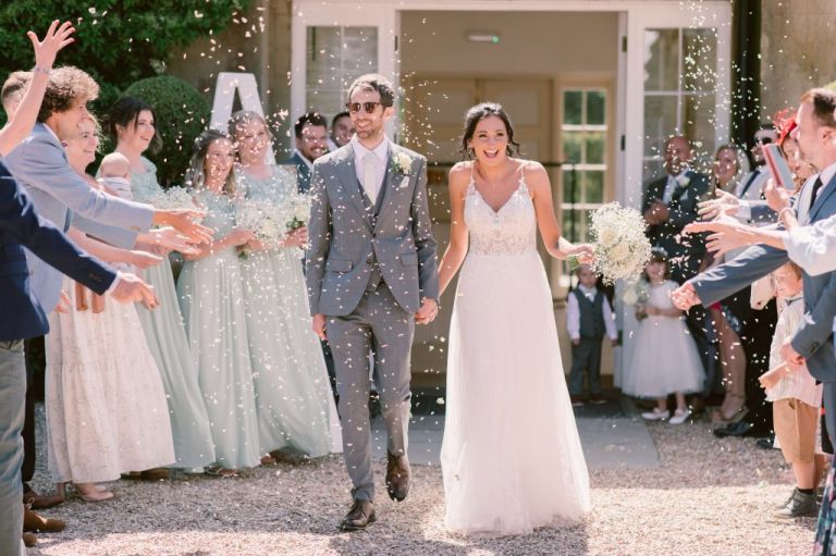 Bride and groom confetti walk through guests