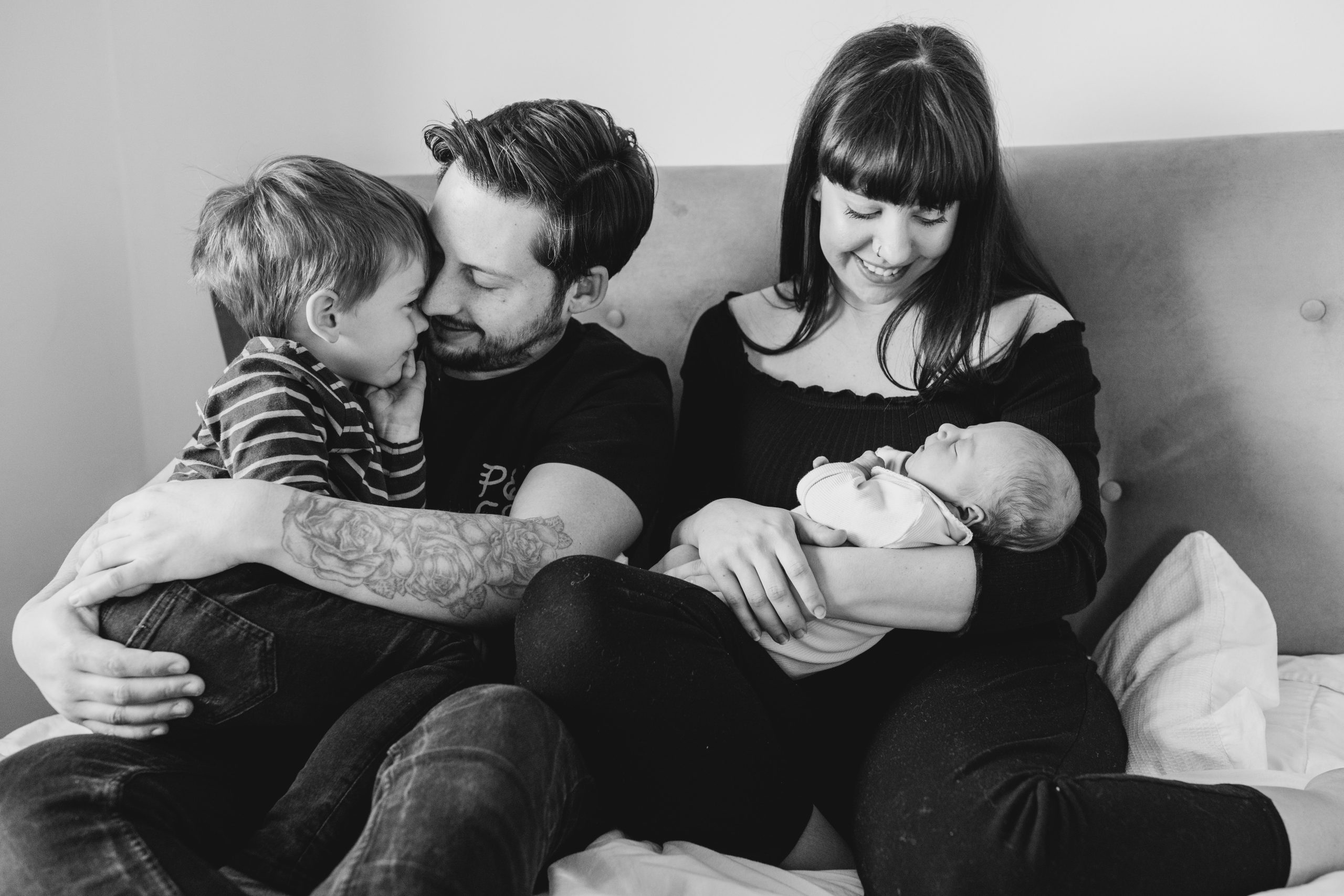 Newborn Family photographer in Hampshire Newborn Family photographer in Hampshire - Black and white photo of young family all snuggling together on the bed with new baby